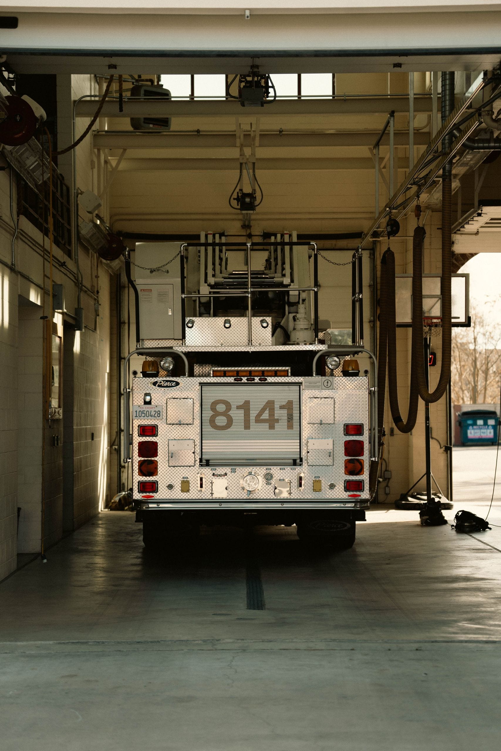 A fire truck parked inside a station garage, showcasing its number 8141 on the rear.
